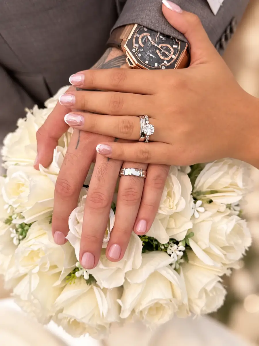 Close-up of wedding rings over an ivory bouquet